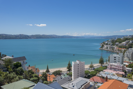 Wellington Harbour and Oriental bay on a fine sunny calm blue sky day showing the calm clear blue water, oriental bay beach, and the various high rise apartment buildingsの写真素材