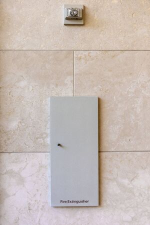 the fire extinguisher panel on a marble tiled wall