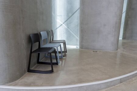 Three chairs in a line against a wall in a modern concrete building
