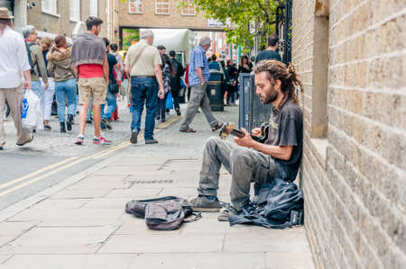 Street musician playing the guitar in the street,  Brick Lane Sunday market, Londonのeditorial素材