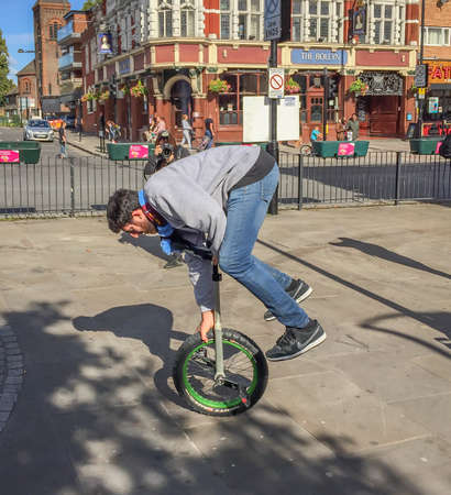 Full length shot of a guy on a unicycle balancing with his hands, Boleyn, Newham, Londonのeditorial素材