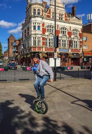 Full length shot of a guy on a unicycle balancing with his hands, Boleyn, Newham, Londonのeditorial素材
