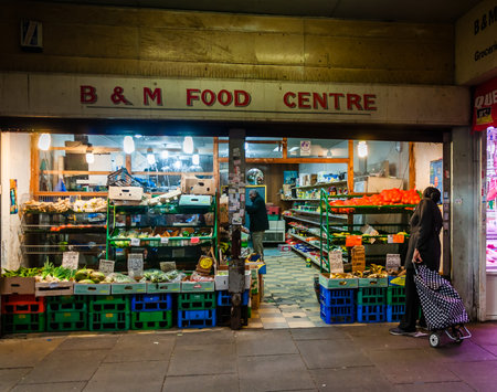 London, United Kingdom, 04 May, 2021: A stall in the covered market, ethnically diverse, selling a mix of household objects and fruit exotic vegetables and halal meatのeditorial素材