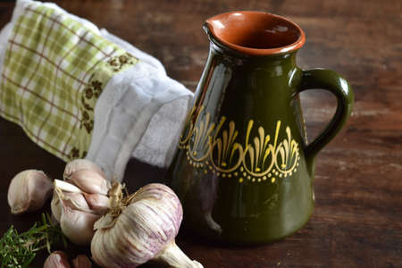 Fresh garlic and rosemary. Ceramic olive oil on rustic wooden table