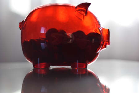 red piggy bank with coins on white background. money, wealth and financial concept.の写真素材