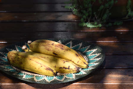 Ripe bananas in rope dish on table in the garden.の写真素材