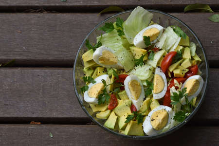 Natural and healthy salad with eggs, lettuce, avocado, tomatoes, olive oil and parsley.の写真素材