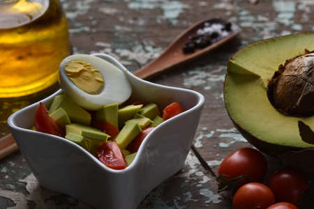 Natural and healthy salad with eggs, lettuce, avocado, tomatoes, olive oil and parsley.