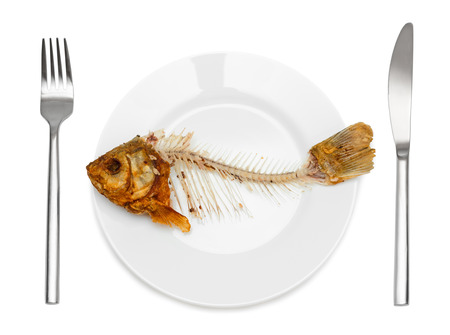 Fish skeleton on the plate - symbol for food shortage and misery. Isolated on white .の写真素材
