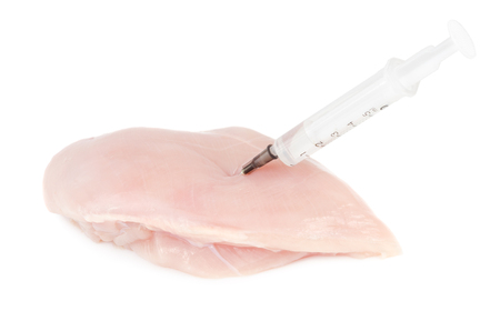 Syringe with liquid being injected to a piece of meat. Conceptual illustration for Hormones and antibiotics in food production. GMO concept. Isolated on white background.の写真素材