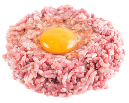 Ground cutlet or raw hamburger with chicken egg yolk isolated on white background. Close-up.の写真素材