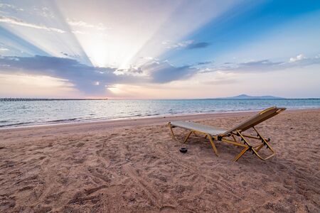 Beautiful sunset on an empty tropical beach. Lonely sunbed on beach of Red sea, Egypt. The sea coast is closed to tourists for quarantine. Resort coast without people . The concept of the collapse of the tourism industry.の写真素材