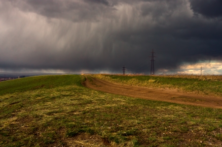 field road, which goes far, far away the storm cloud hanging low over the ground and which are clearly visible torrents of rain, rushing to the groundの写真素材