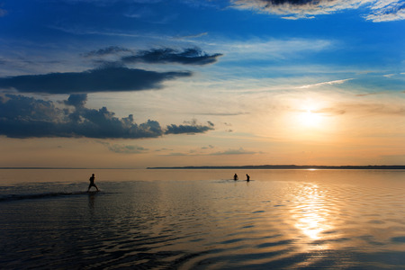 Young people swimming in the river at sunsetの写真素材