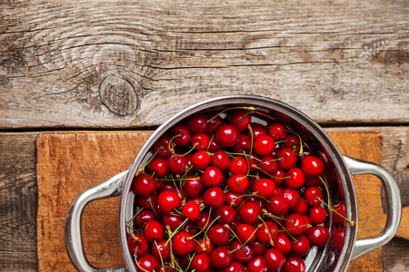 Sweet cherries in colander on color wooden の写真素材