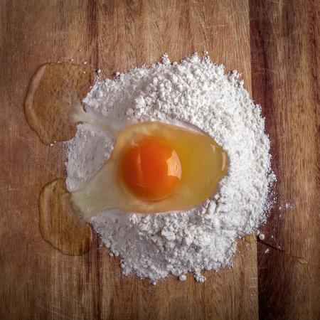 broken egg in flour on cutting boardの写真素材