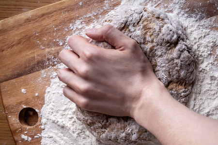 female hands knead the dough for breadの写真素材