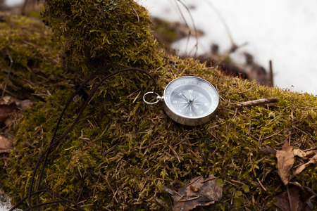 compass in winter forest on a mossy logの写真素材
