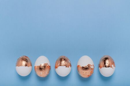 Minimalistic background. Golden eggs are arranged in a straight line.
