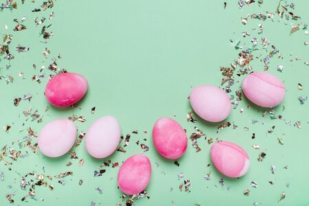 Cute light green background with pink eggs and gold confetti.