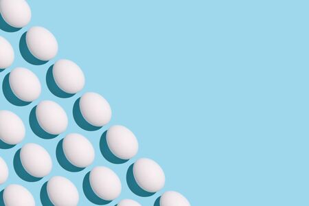 Happy Easter - modern minimalistic greeting card. White eggs on light blue background, place for textの写真素材