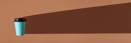 Brown background with one paper blue cup. Trend hard shadow. Banner with place for your text.の写真素材