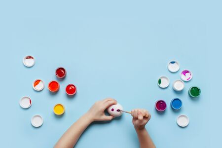 A child paints a white egg. Top view, place for your text.