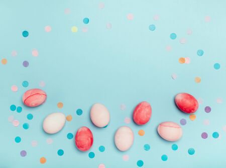 Cute light blue background with pink eggs and confetti.