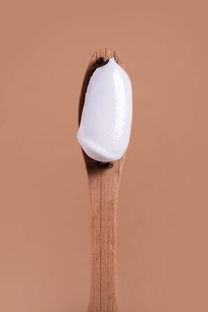 Wooden toothbrush with white paste close-up on a brown background.の写真素材