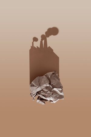 A clump of crumpled paper casts a hard shadow in the shape of a garbage recycling plant. Environmental protection conceptの写真素材
