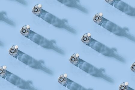 Many bottles stand on a blue background, a beautiful shadow with highlights of light. Modern trendy...