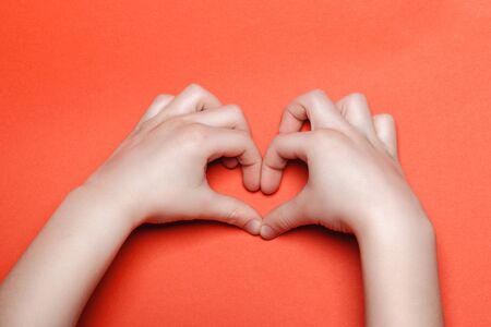 Child make a heart on a red