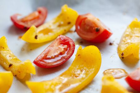 Slices of yellow bell pepper and red tomato prepared for baking with spices, close upの写真素材