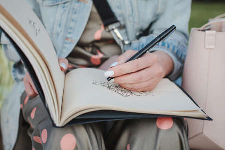 Sketchbook with a drawing of a house close-up. Girl draws in the fresh air. Front viewの写真素材
