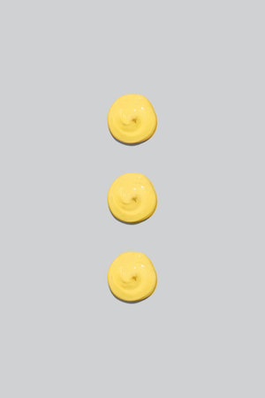 Three spots of yellow paint on a gray background. Cream, cosmetic, topping for your design.