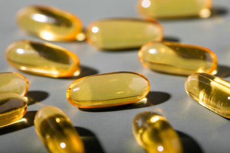 Yellow gelatin capsules on a gray background. Food supplement, vitamin D, omega, vitamin C, multivitamins. Soft focusの写真素材