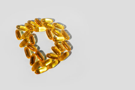 Yellow gelatin capsules on a gray background in the shape of the letter D. Food supplement, vitamin D.の写真素材