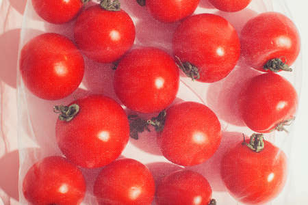 Reusable packaging of products by weight. Red tomatoes in a reusable bag close up on a pink background.の写真素材
