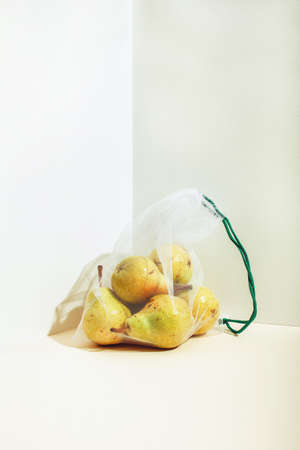 Reusable packaging of products by weight. Pears in a reusable bag close up on a pink background. Isometric viewの写真素材