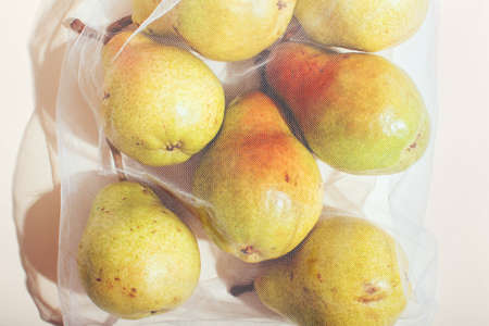 Reusable packaging of products by weight. Pears in a reusable bag close up on a pink backgroundの写真素材