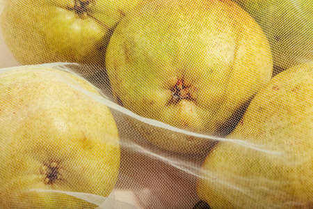 Reusable packaging of products by weight. Pears in a reusable bag close up on a pink background