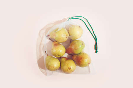 Reusable packaging of products by weight. Pears in a reusable bag close up on a pink backgroundの写真素材