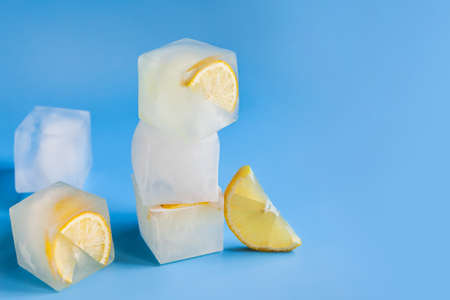 Modern composition of the frozen slices of lemon and ice cubes on a blue backgroundの写真素材