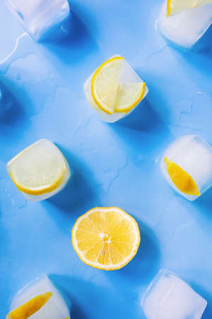 Modern geometric composition of the frozen slices of lemon and ice cubes on a blue backgroundの写真素材