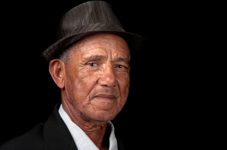 An old man with a hat looks at the camera 