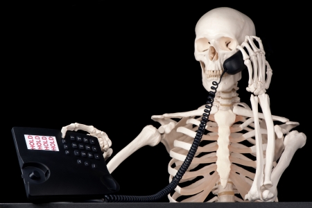A skeletal call centre employee keeps a call on hold forever の写真素材