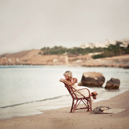 pensive woman sitting on the dunes watching the sea の写真素材