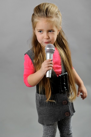 little girl singing karaoke on a gray backgroundの写真素材