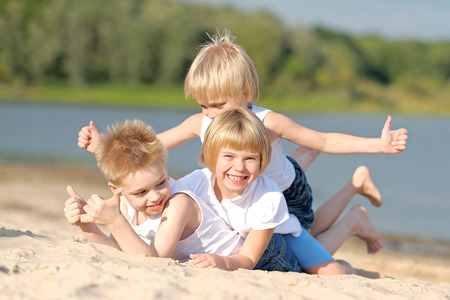 Portrait of three children playing on the beachの写真素材