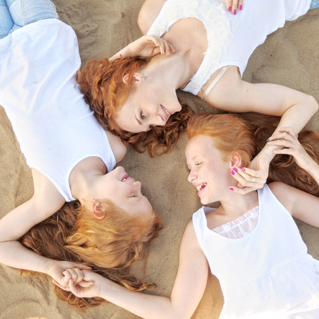 mother and her two daughters on the beach in summerの写真素材